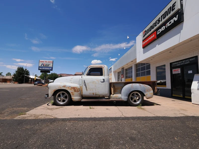 Old white pickup truck parked outside building