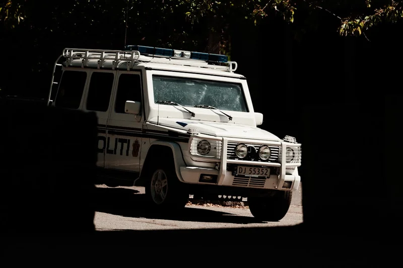 A white police suv is parked in the shadows.