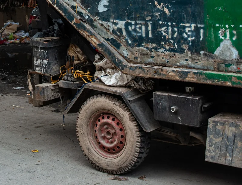 Close-up of a dirty garbage truck with a flat tire